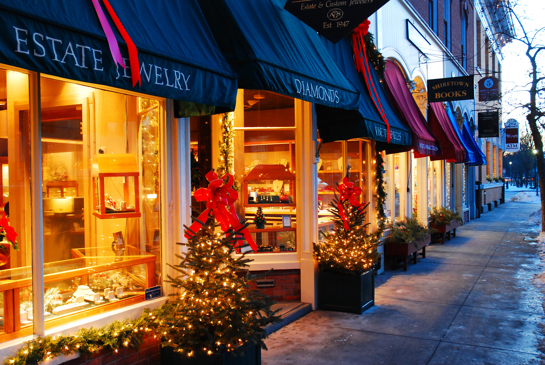 Christmas lights and decorations shine on a storefront, giving a cozy feel.