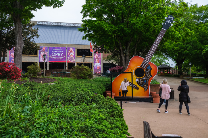 Exterior view of the Grand Ole Opry building in Nashville, TN, featuring its iconic signage and well-lit entrance.