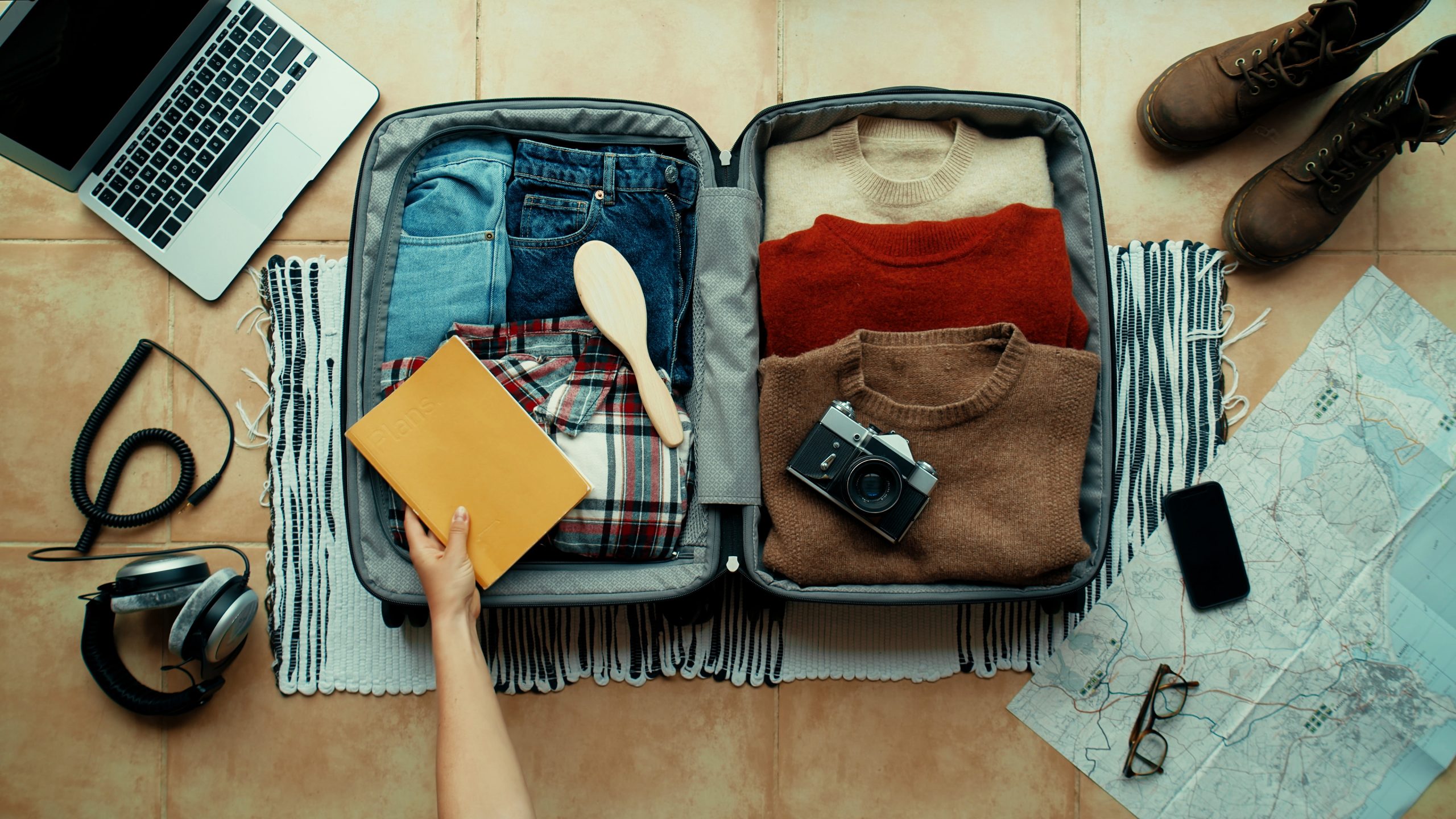 Prepping for travel by packing suitcase with clothes and essentials.