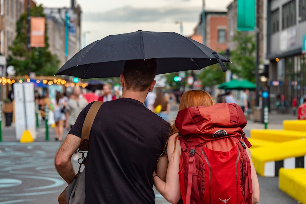 A tourist couple holding umbrella in the city while it rains