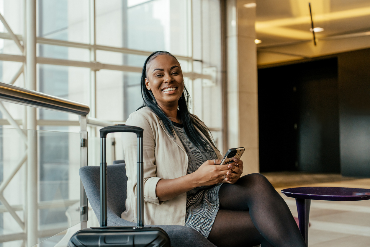 Female business traveler waiting at hotel lobby with suitcase during business trip
